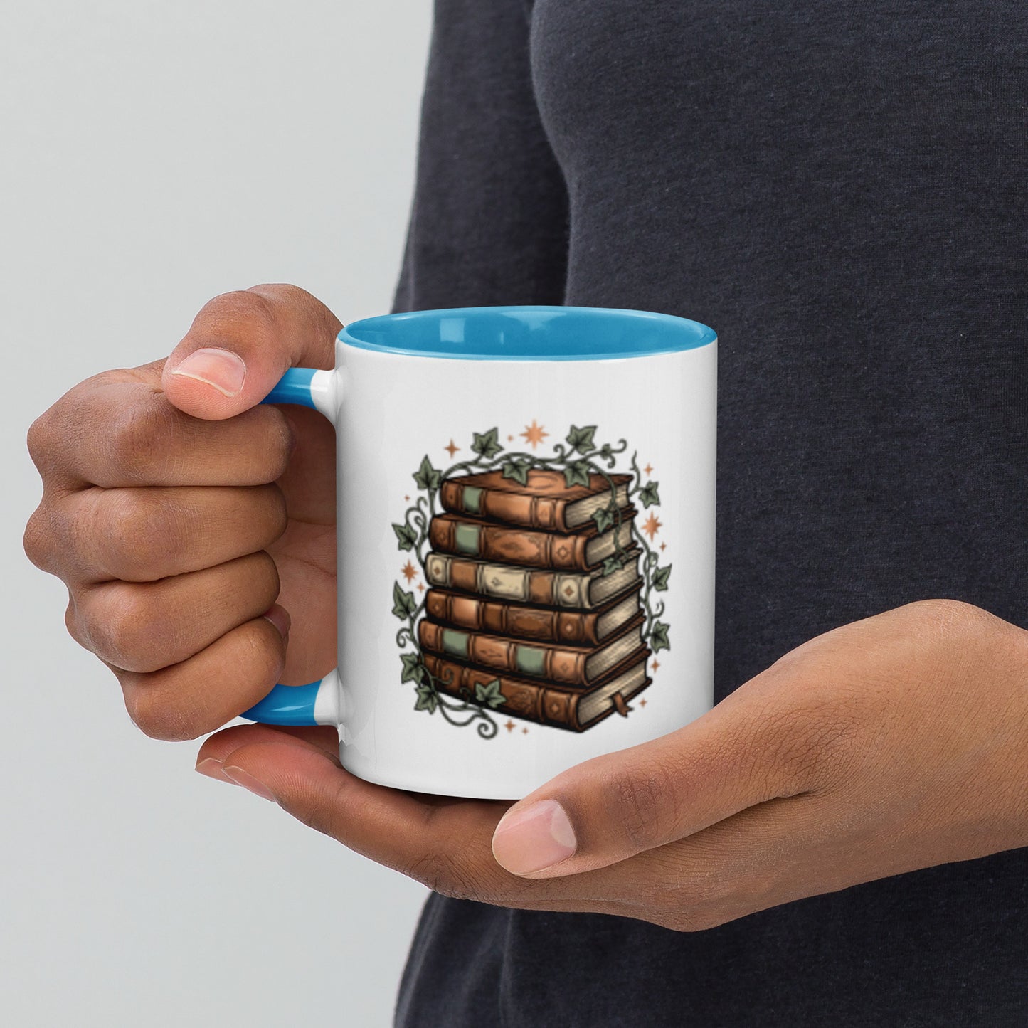 Stacked books and ivy design on a white ceramic mug with blue rim and handle, 11 oz, left view