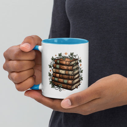 Stacked books and ivy design on a white ceramic mug with blue rim and handle, 11 oz, left view
