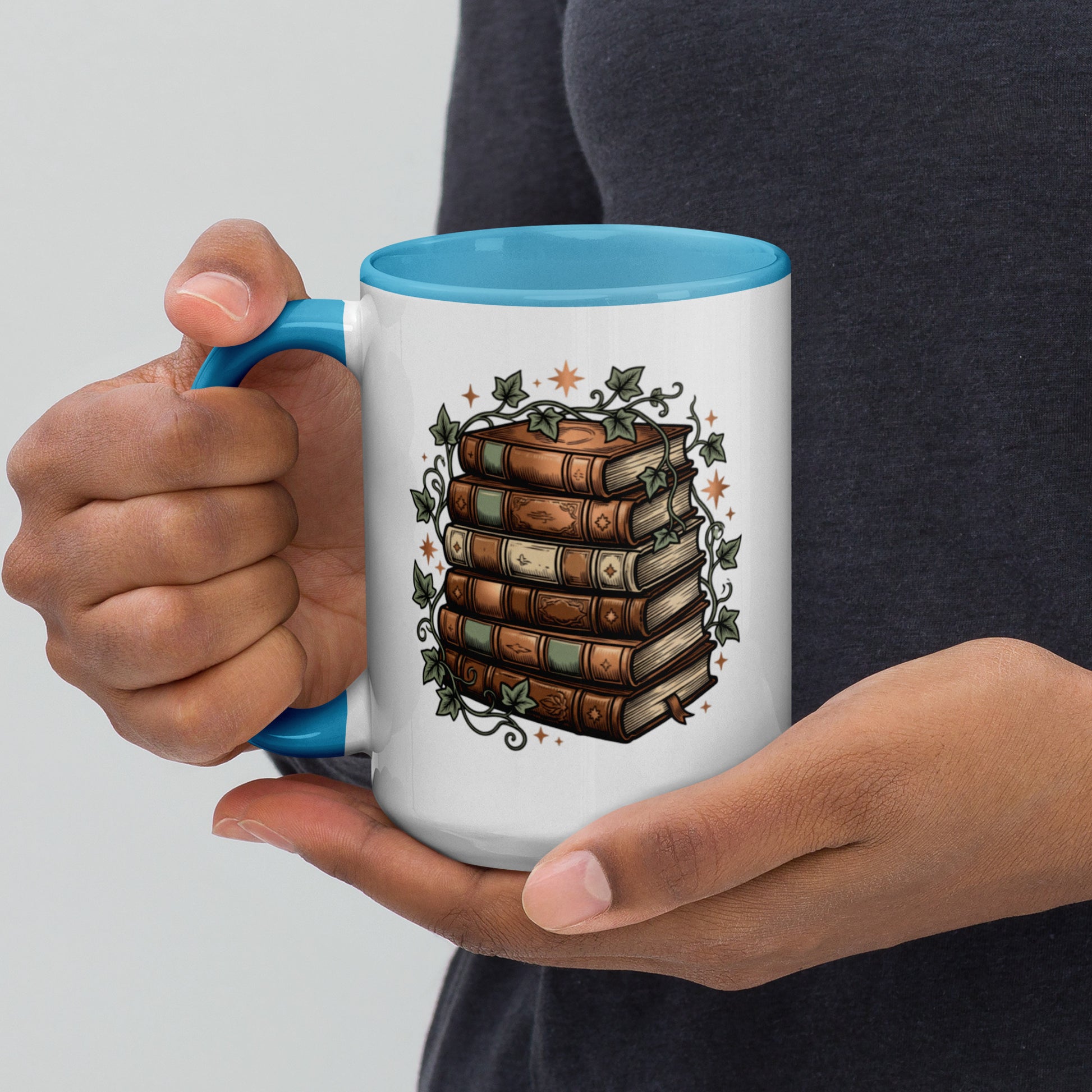 Stacked books and ivy design on a white ceramic mug with blue rim and handle, 15 oz, left view