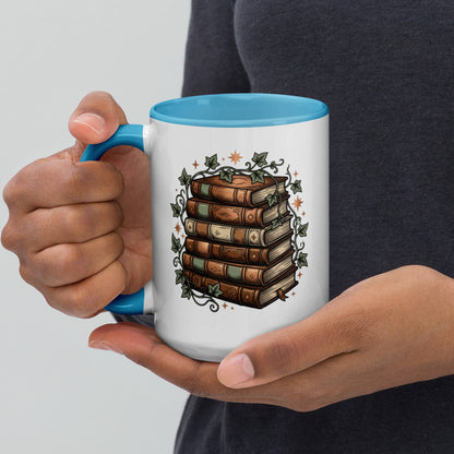 Stacked books and ivy design on a white ceramic mug with blue rim and handle, 15 oz, left view
