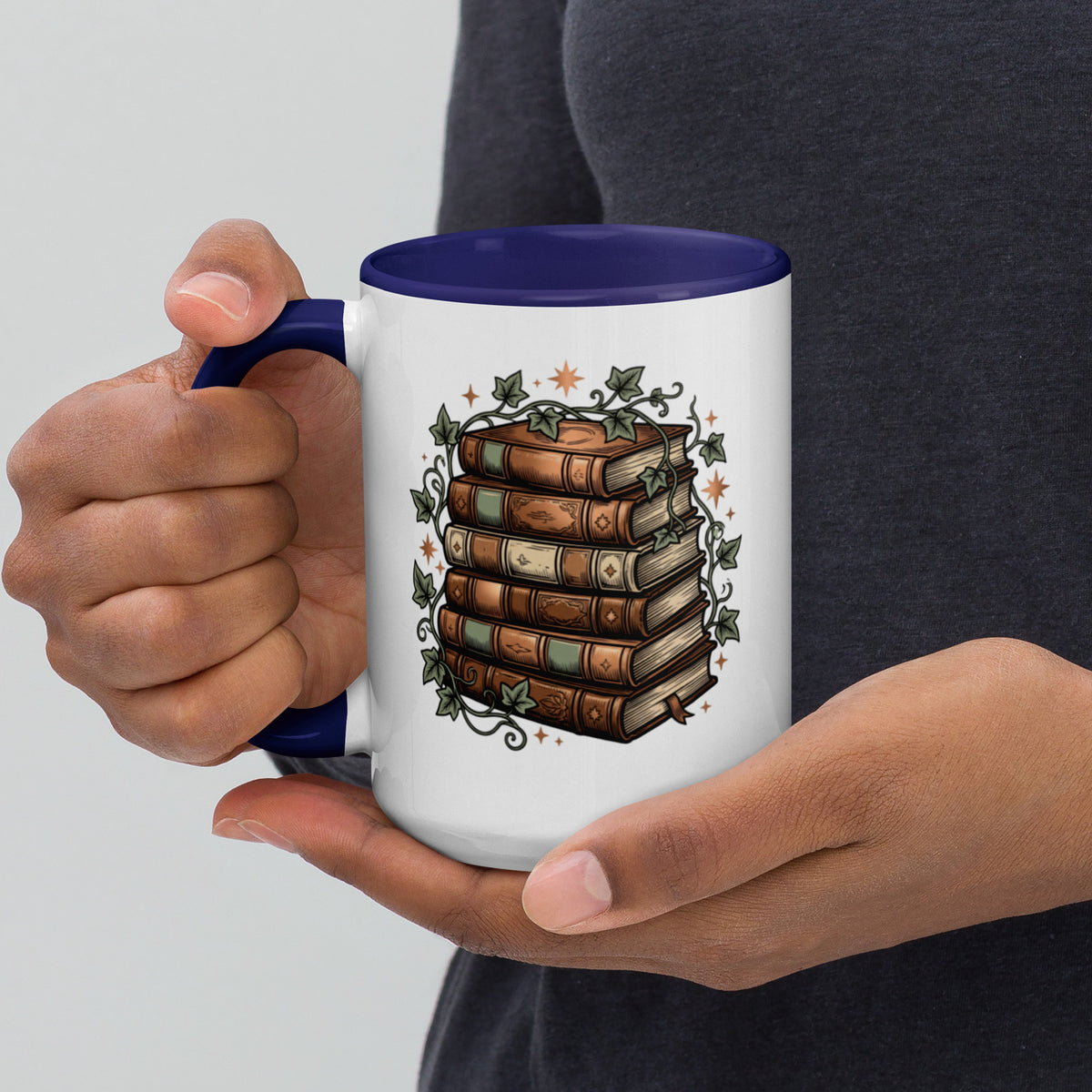 Stacked books and ivy design on a white ceramic mug with dark blue rim and handle, 15 oz, left view