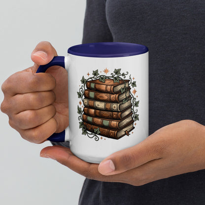 Stacked books and ivy design on a white ceramic mug with dark blue rim and handle, 15 oz, left view