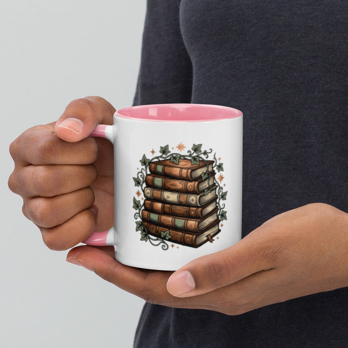 Stacked books and ivy design on a white ceramic mug with pink rim and handle, 11 oz, left view