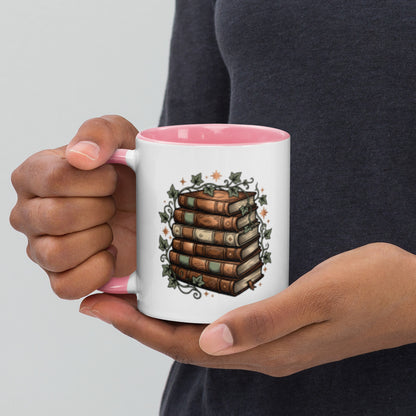 Stacked books and ivy design on a white ceramic mug with pink rim and handle, 11 oz, left view