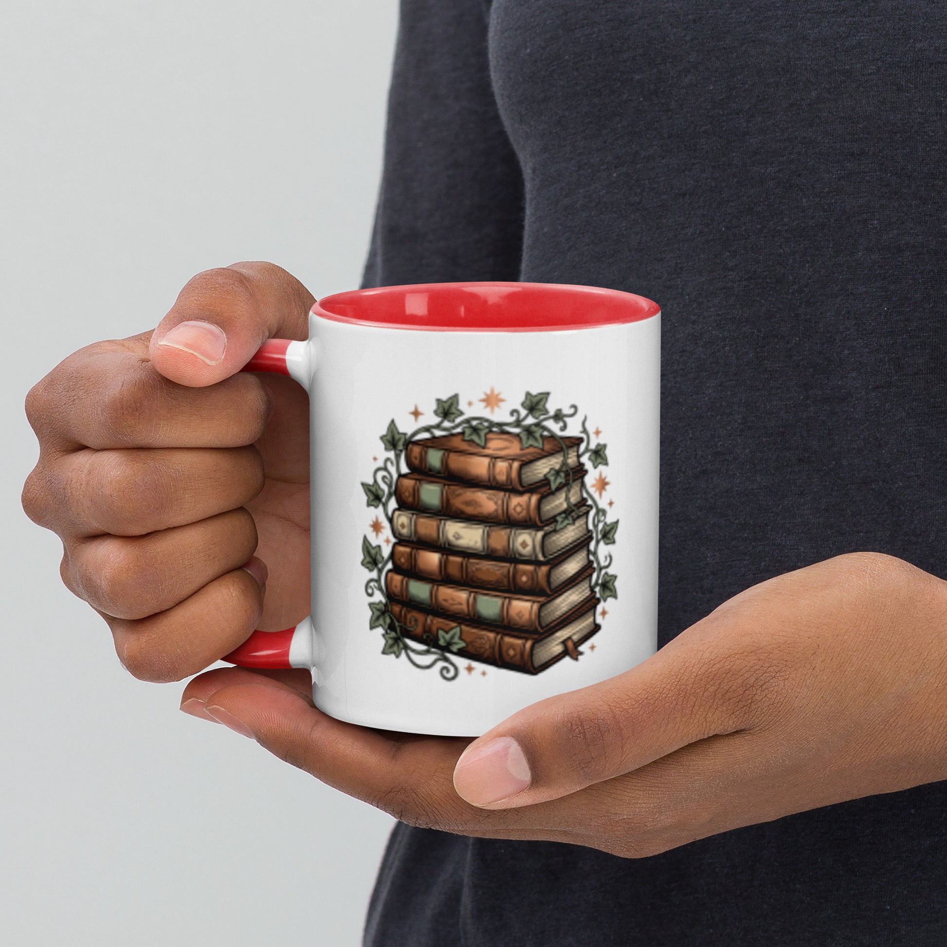 Stacked books and ivy design on a white ceramic mug with red rim and handle, 11 oz, left view