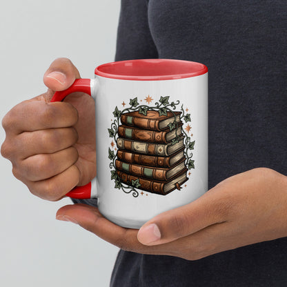 Stacked books and ivy design on a white ceramic mug with red rim and handle, 15 oz, left view