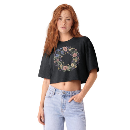 Pastel wildflower wreath printed on a washed black garment-dyed cropped tee, front view