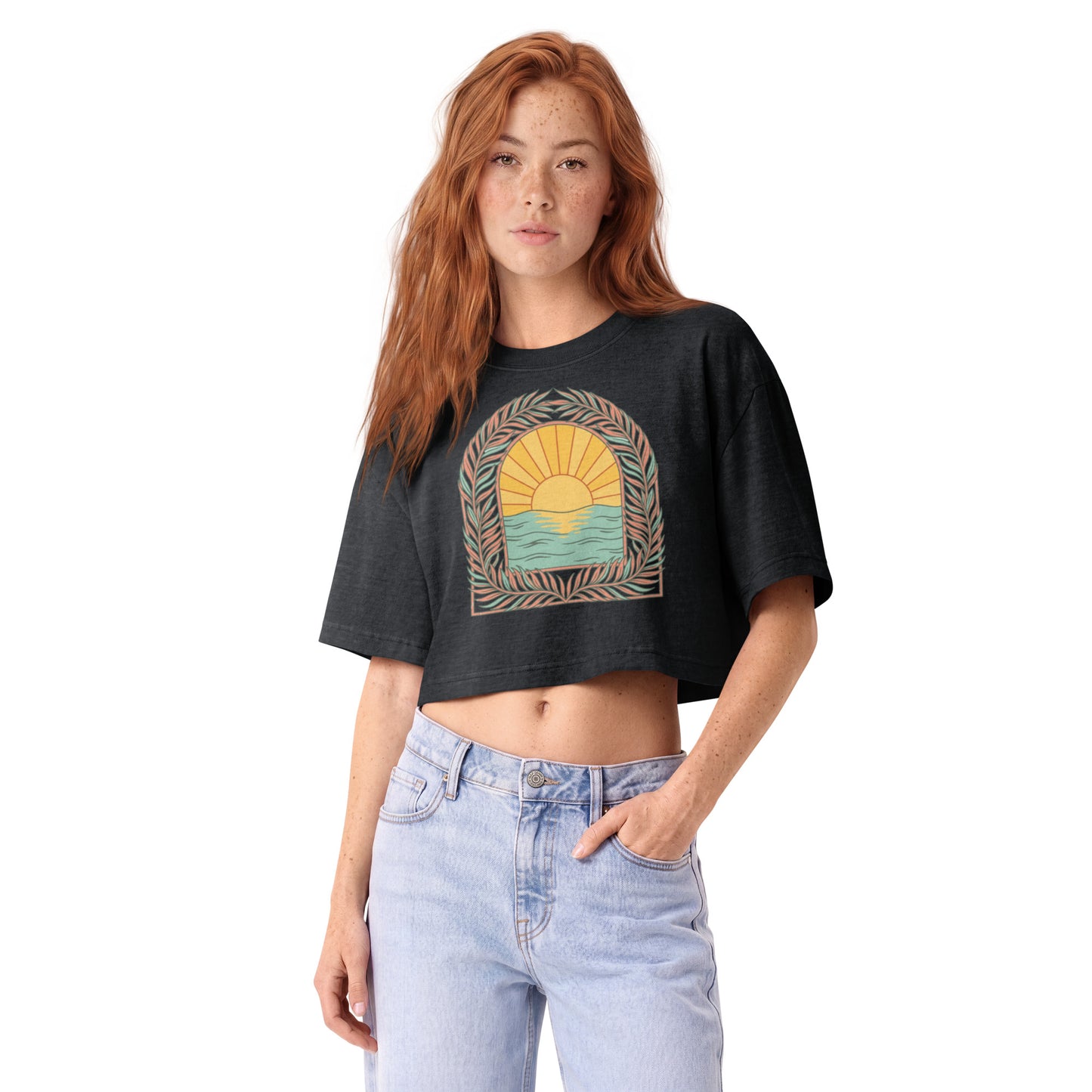 Retro sunrise and ocean arch framed in botanicals on a washed black garment-dyed cropped tee, front view
